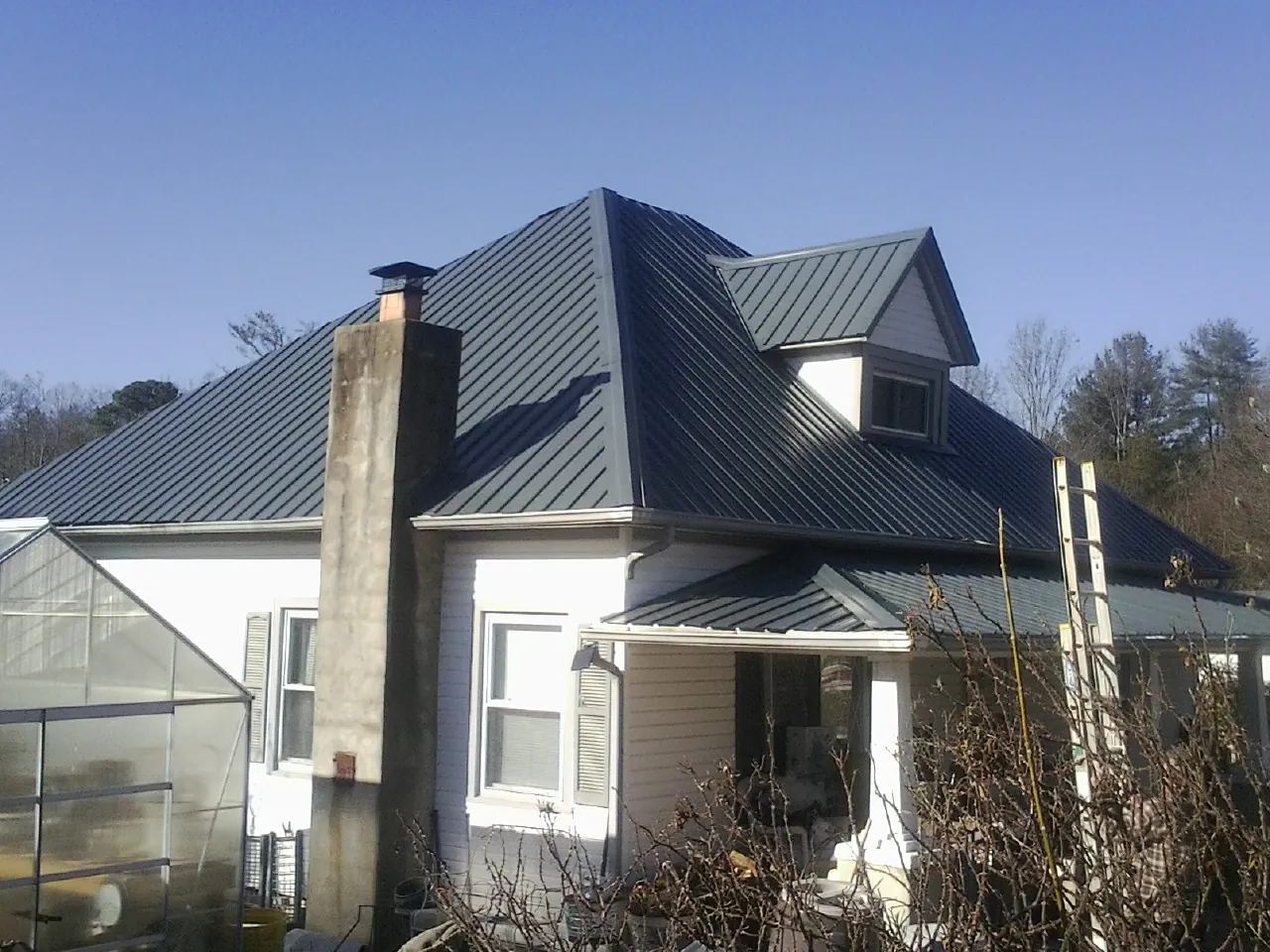Dark blue standing seam metal roof on a white farmhouse with dormer — Slate & Tile Roof Repair by Roofing Brothers in Erin