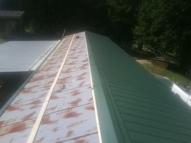 Old rusted panels beside newly installed green metal roofing — Wind Damage Roof Repair by Roofing Brothers in Erin