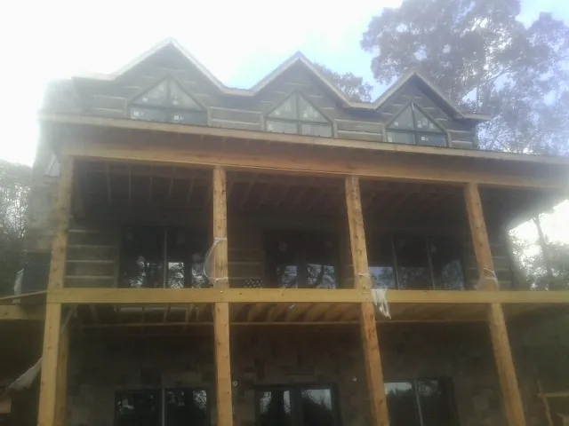 Dormers and porch framing on a large log home under construction — Roof Coating work by our crew in Erin
